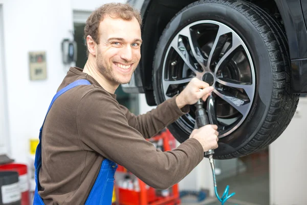 Mécanicien changeant de roues sur une voiture sur rampe hydraulique — Photo