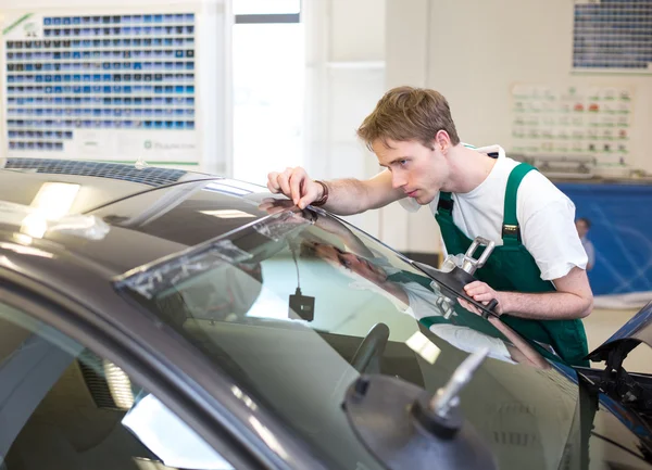 Worker in glazier's workshop installs windshield — Stock Photo, Image