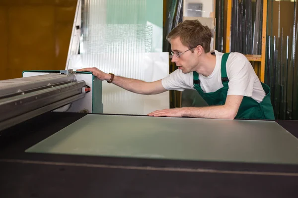 Рабочий в мастерской глазури готовит стекло для резки — стоковое фото