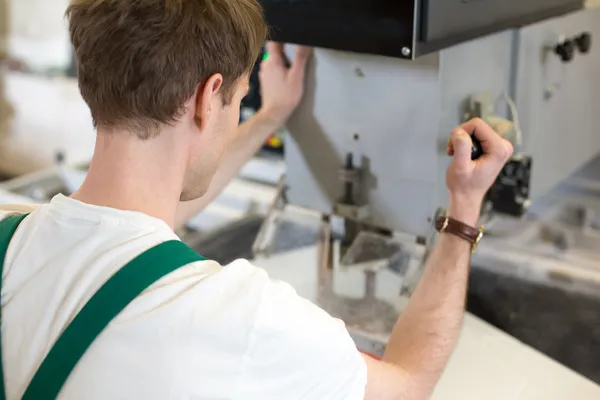 Worker operates glass drilling machine — Stock Photo, Image