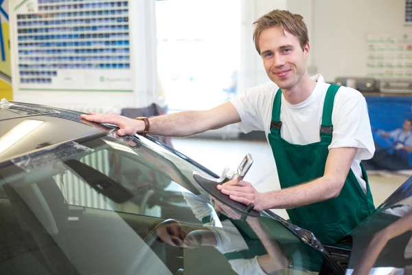 Worker in glazier's workshop installs windshield — Stock Photo, Image