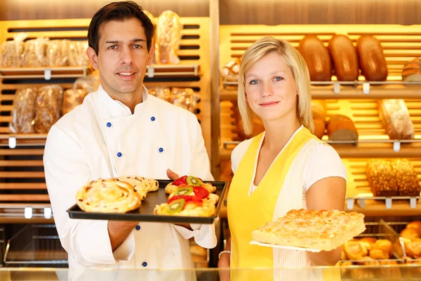 Baker and shopkeeper present pastry — Stock Photo, Image