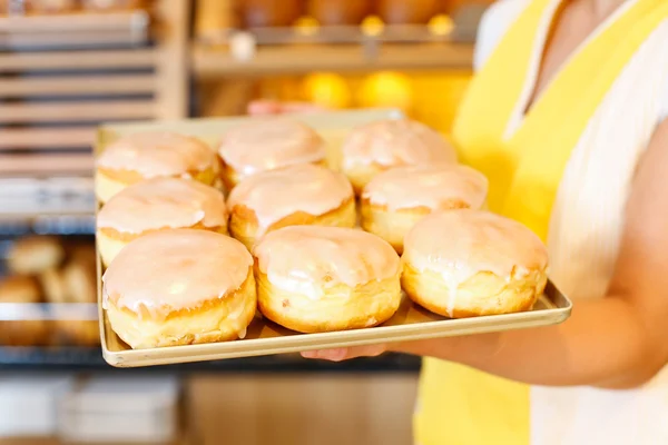 Bakery shopkeeper presents doughnuts — Stock Photo, Image