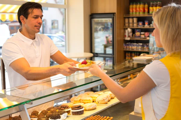 Shopkeeper giving pastry to customer — Stock Photo, Image