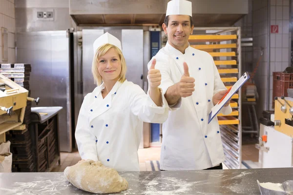 Twee bakkers met Duimschroef opwaarts in bakkerij — Stockfoto