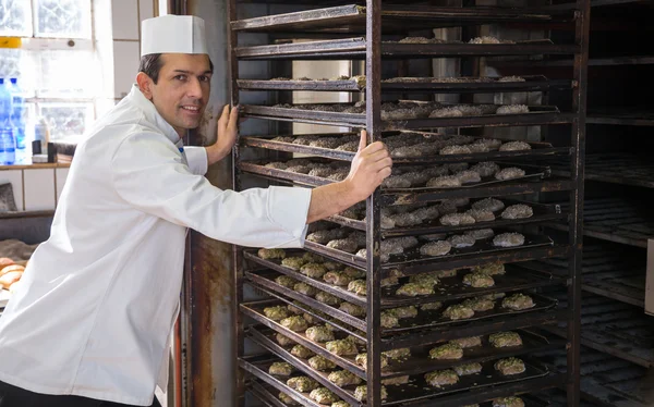 Baker colocando um rack de pão no forno — Fotografia de Stock