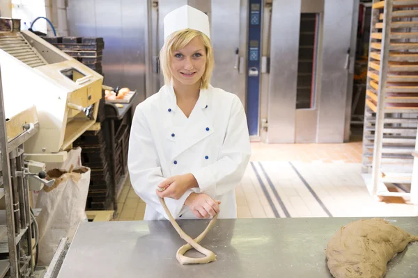 Baker forming pretzel out of dough — Stock Photo, Image