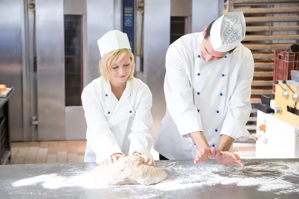 Baker učeň instrukce v hnětení těsta — Stock fotografie