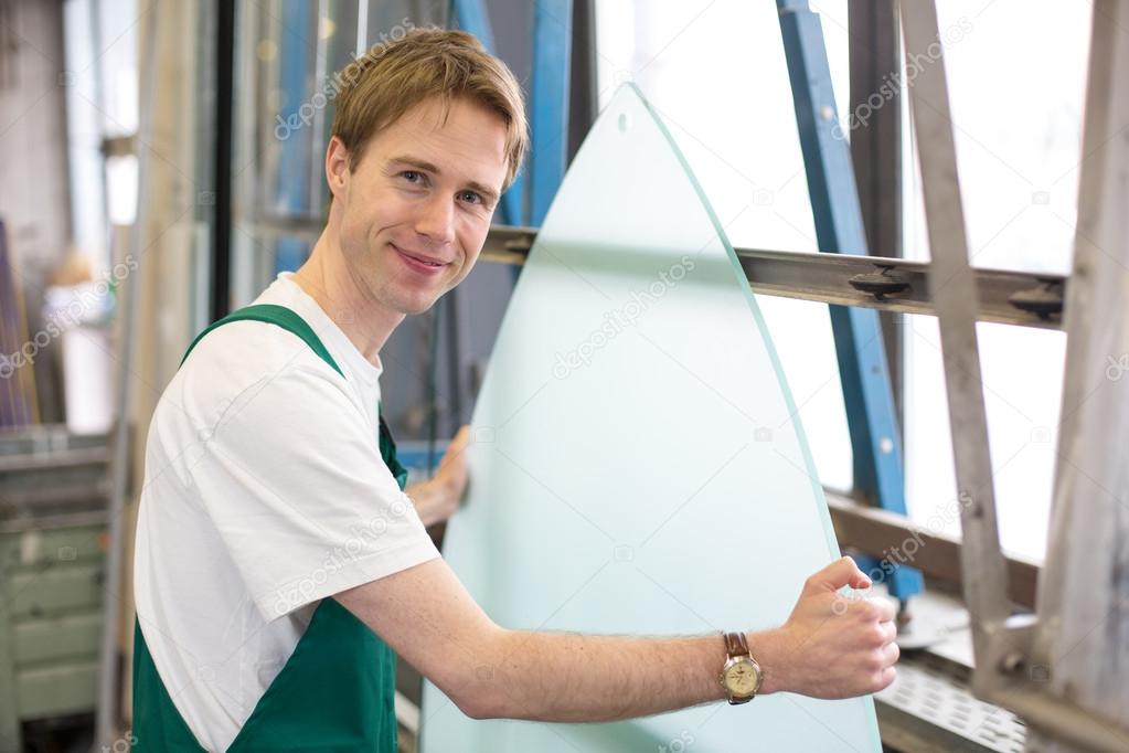 Worker in glazier's workshop handling glass