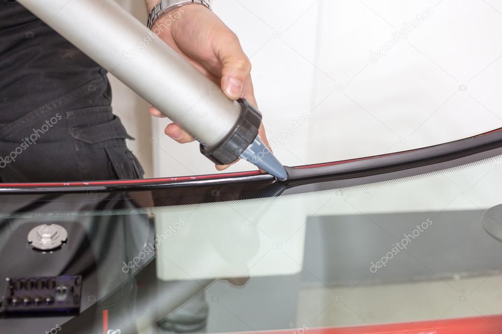 Glazier applying rubber sealing to windscreen