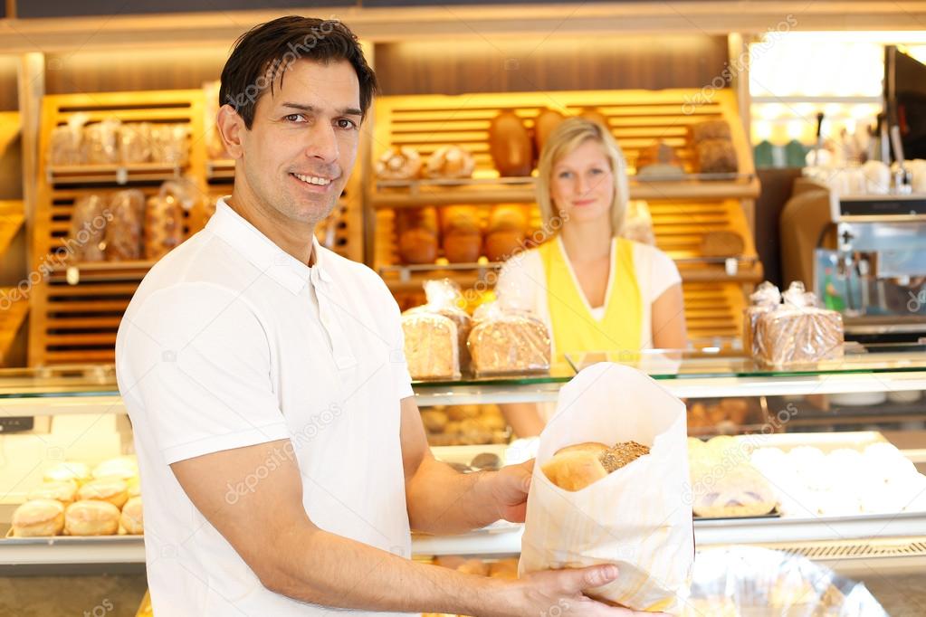 Happy customer in bakery with bags of bread