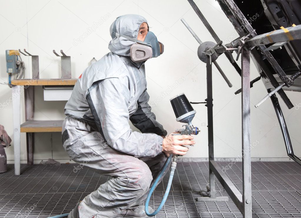 Car body painter spraying paint on bodywork parts Stock Photo by