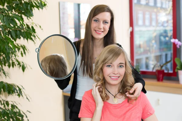 Friseurin zeigt Kundin ihren neuen Haarschnitt — Stockfoto