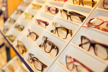Eyeglasses, shades and sunglasses in optometrist's shop clipart