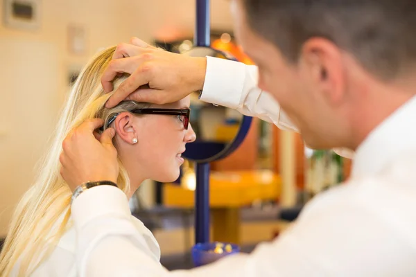 Optician examining correct fit of eyeglass frame for customer — Stock Photo, Image