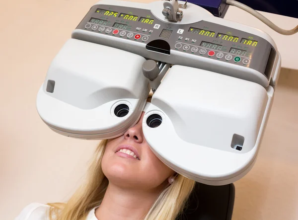 Kund hos en optiker eller optikern tittar genom phoropter — Stockfoto