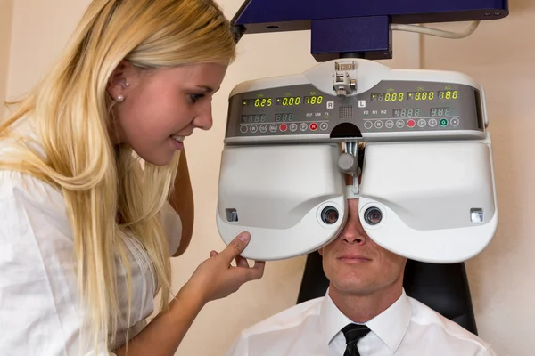 Optician or optometrist and patient with a phoropter — Stock Photo, Image