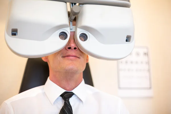 Customer of a optometrist or optician looking through phoropter — Stock Photo, Image