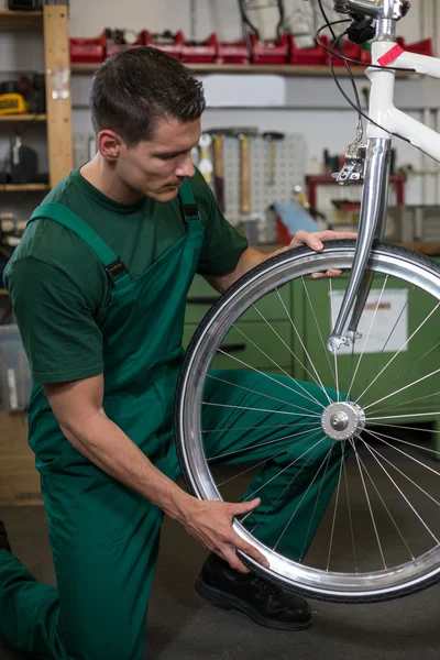 Bicycle mechanic repairing wheel on bike in a workshop — Stock Photo, Image