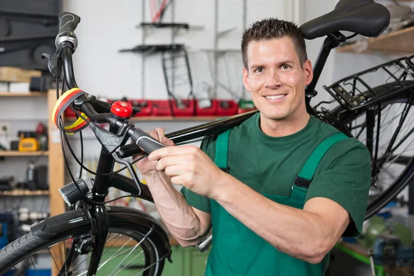 Cykel mekaniker bär en cykel i workshop — Stockfoto