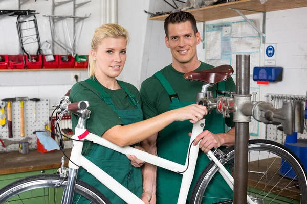 Mecánico de bicicletas y aprendiz reparando una bicicleta — Foto de Stock