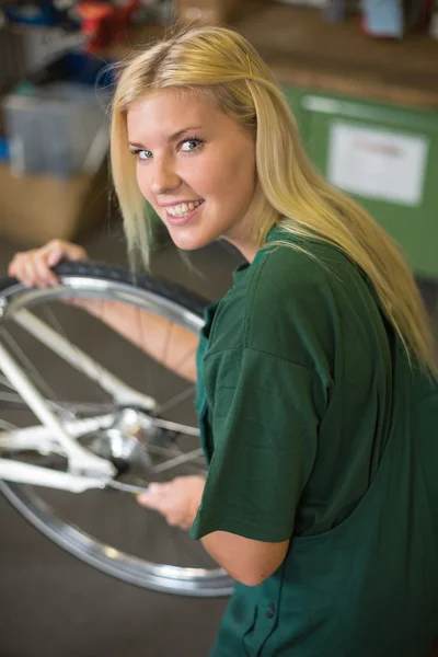 Female mechanic in workshop installing or repairing a bicycle — Stock Photo, Image