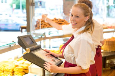 Cashier in baker's shop posing with cash register clipart