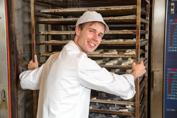 Bäcker füllt Backofen in Bäckerei oder Backstube — Stockfoto