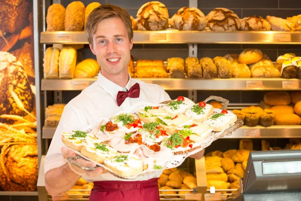 Winkelier in bakkerij met tablet van broodjes — Stockfoto