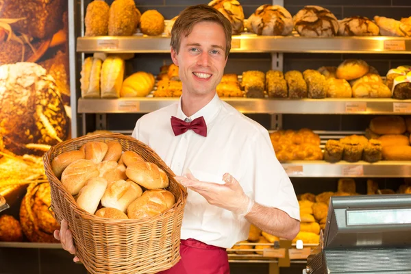 Panettiere con cesto pieno di pane in panetteria — Foto Stock