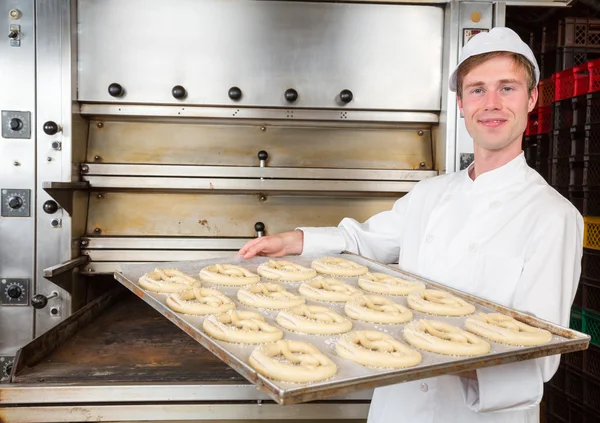 Baker with baking plate full of pretzels — Stock Photo, Image