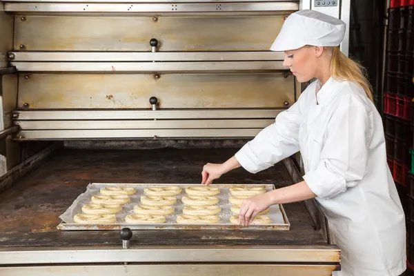 Panadero en panadería con placa para hornear llena de pretzels —  Fotos de Stock