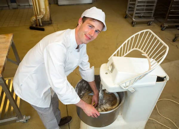 Bakker met deeg kneden machine in de bakkerij — Stockfoto