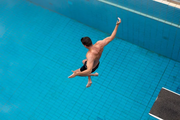 Homem salta da prancha de mergulho na piscina — Fotografia de Stock