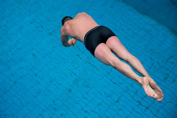 Man jumps from diving board at swimming pool — Stock Photo, Image