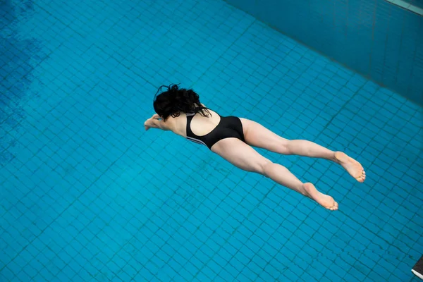 Girl jumps from a diving board at swimming pool — Stock Photo, Image