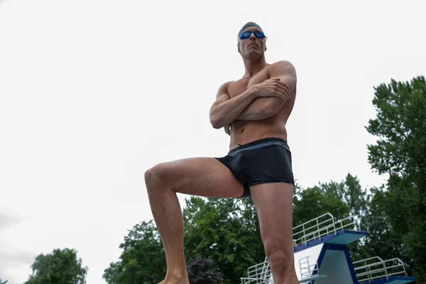 Uomo in posa sul blocco di partenza in piscina — Foto Stock