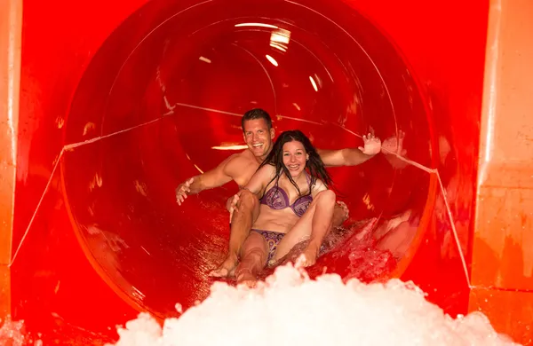 Couple in water slide at public swimming pool — Stock Photo, Image
