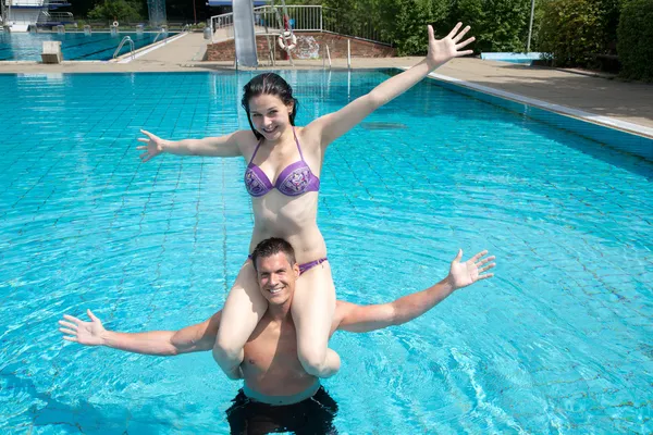 Chica sentada sobre los hombros del hombre en la piscina — Foto de Stock