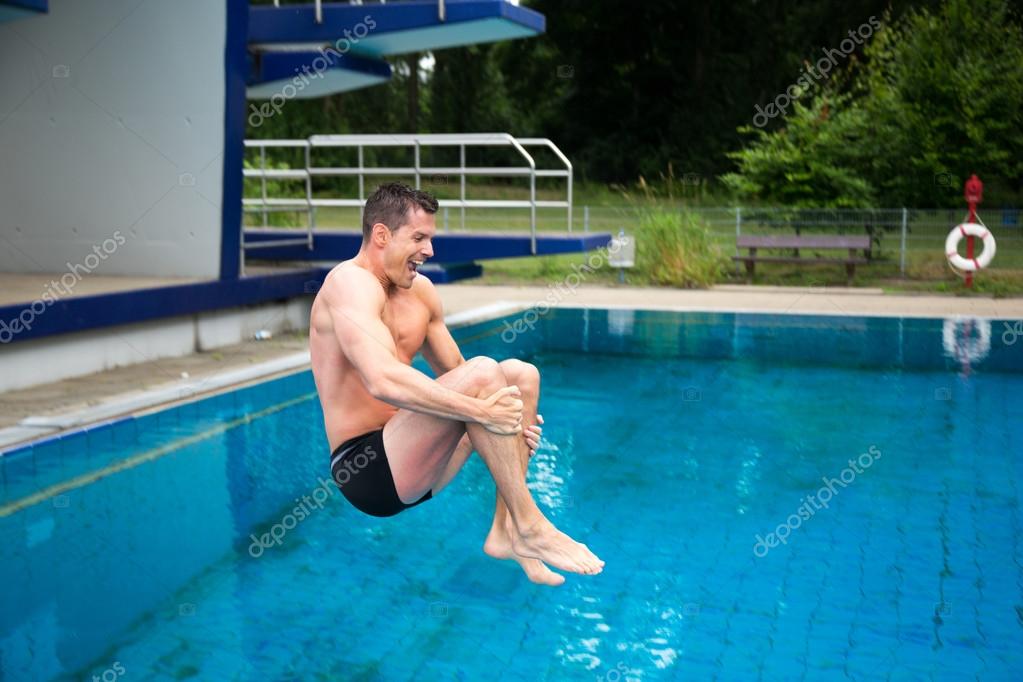 Man having fun jumping from diving board at swimming pool Stock Photo by  ©Ikonoklast 30562907