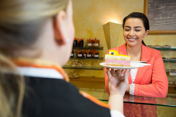 Waitress serving cake to customer in cafe