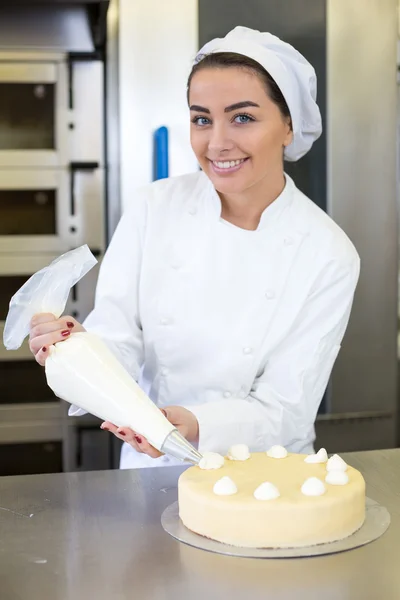 Baker prepares cake in bakehouse with whipped cream — Stock Photo, Image