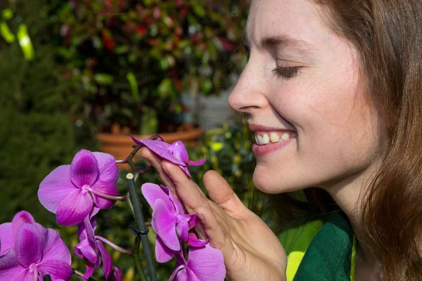 Mujer oliendo a flor de orquídea —  Fotos de Stock