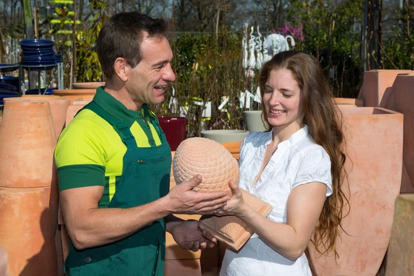 Employee in garden center selling pottery to customer — Stock Photo, Image