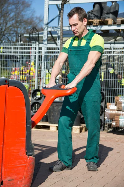 Worker with forklift in warehouse or storehouse — Stock Photo, Image