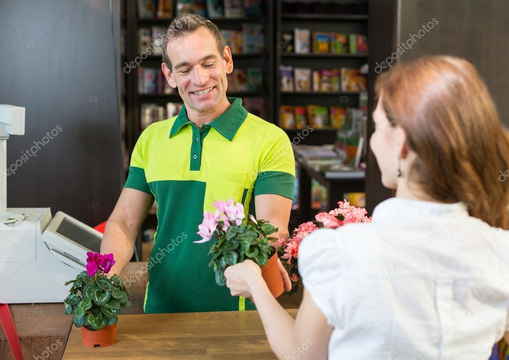 Cashier or shopkeeper in flower shop or retail store serving client