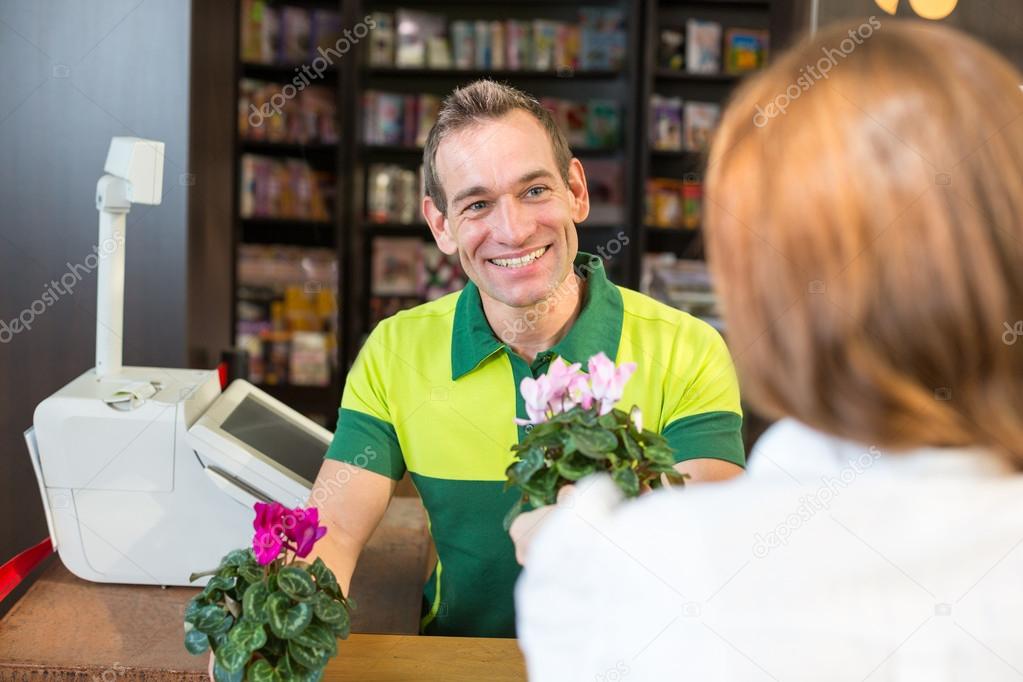 Cashier or shopkeeper in flower shop or retail store serving client