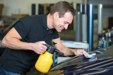 kumaş ve sprey şişe ile araba temizlik işçisi