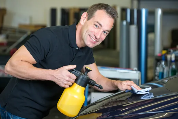 Werknemer schoonmaken auto met doek en spray fles — Stockfoto