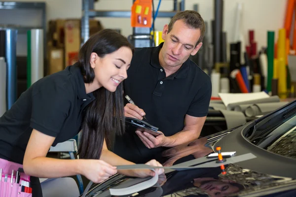 Instructor and apprentice in car wrapping workshop — Stock Photo, Image